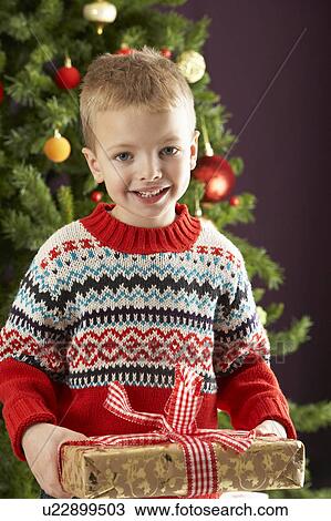 Young Boy Holding Christmas Present In Front Of Christmas Tree View Large Photo Image Stock Image - Young Boy Holding Christmas Present In Front Of Christmas Tree. Fotosearch