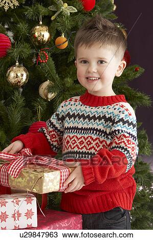 Young Boy Holding Christmas Present In Front Of Christmas Tree View Large Photo Image Stock Image - Young Boy Holding Christmas Present In Front Of Christmas Tree. Fotosearch