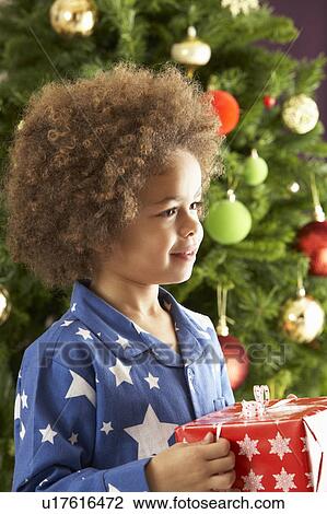 Young Boy Holding Gift In Front Of Christmas Tree View Large Photo Image Stock Image - Young Boy Holding Gift In Front Of Christmas Tree. Fotosearch