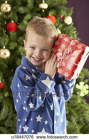 Young Boy Holding Wrapped Present In Front Of Christmas Tree View Large Photo Image Stock Photograph - Young Boy Holding Wrapped Present In Front Of Christmas Tree. Fotosearch