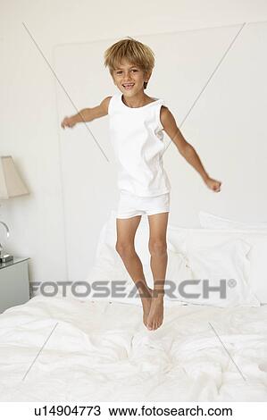Stock Image - Young Boy Jumping On Bed. Fotosearch