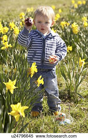 Stock Photography - Young Boy On Easter Egg Hunt In Daffodil Field. Fotosearch