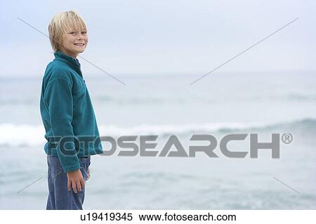 Young Boy On Holiday Standing On Winter Beach Looking Out To Sea View Large Photo Image Stock Photography - Young Boy On Holiday Standing On Winter Beach Looking Out To Sea. Fotosearch