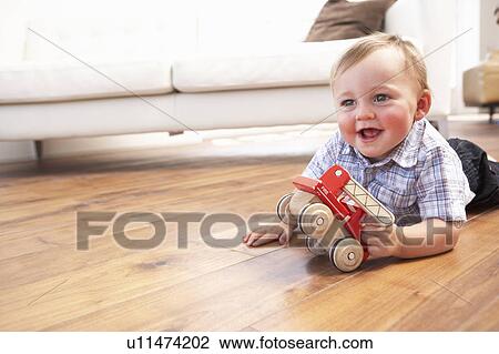Stock Image - Young Boy Playing With Wooden Toy Car At Home. Fotosearch