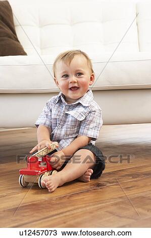 Stock Image - Young Boy Playing With Wooden Toy Car At Home. Fotosearch