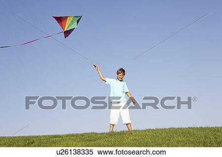 Stock Photography - Young boy poses with kite in a field. Fotosearch