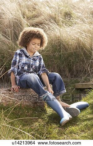 Picture - Young Boy Putting On Wellington Boots. Fotosearch