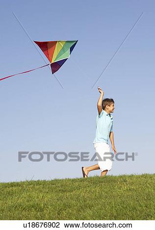 Stock Image - Young boy runs with kite through field. Fotosearch