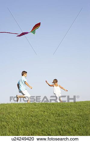 Young children run with kite through field View Large Photo Image Stock Image - Young children run with kite through field. Fotosearch