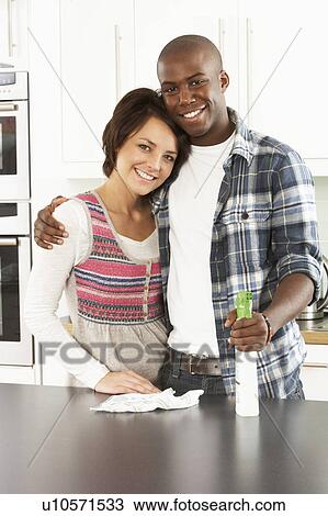 Stock Image - Young Couple Cleaning Cleaning Modern Kitchen . Fotosearch