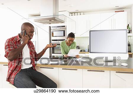 Young Couple Discussing Personal Finances In Modern Kitchen View Large Photo Image Stock Image - Young Couple Discussing Personal Finances In Modern Kitchen . Fotosearch