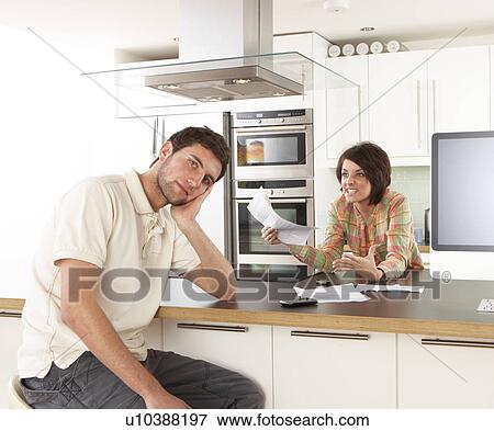 Young Couple Discussing Personal Finances In Modern Kitchen View Large Photo Image Stock Photo - Young Couple Discussing Personal Finances In Modern Kitchen . Fotosearch