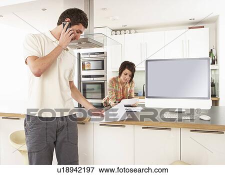Young Couple Discussing Personal Finances In Modern Kitchen View Large Photo Image Stock Photo - Young Couple Discussing Personal Finances In Modern Kitchen . Fotosearch