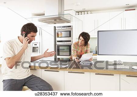 Stock Photo - Young Couple Discussing Personal Finances In Modern Kitchen . Fotosearch