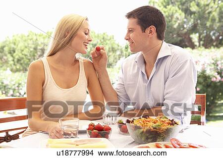 Picture - Young couple eating outdoors. Fotosearch