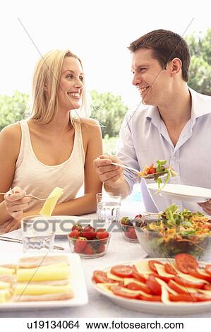 Picture - Young couple eating outdoors. Fotosearch