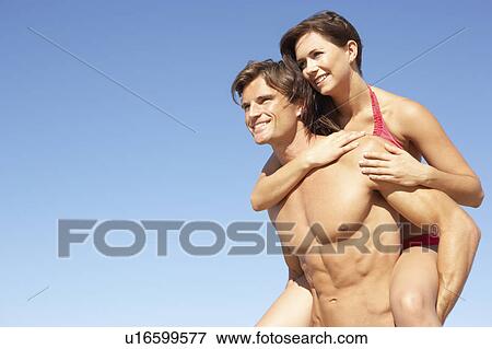 Young Couple Enjoying Piggyback On Beach Holiday View Large Photo Image Stock Photo - Young Couple Enjoying Piggyback On Beach Holiday. Fotosearch