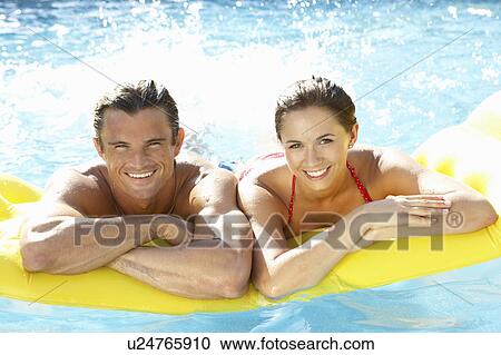 Stock Image - Young couple having fun in pool. Fotosearch
