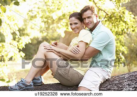 Stock Photo - Young Couple In Walking Clothes Resting On Tree In Park. Fotosearch