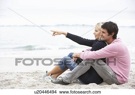 Picture - Young Couple On Holiday Sitting On Winter Beach. Fotosearch