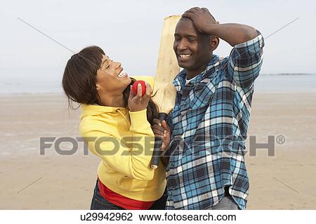Stock Image - Young Couple Playing Cricket On Autumn Beach Holiday. Fotosearch