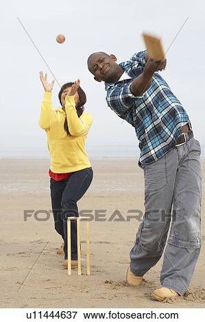 Stock Photo - Young Couple Playing Cricket On Autumn Beach Holiday. Fotosearch