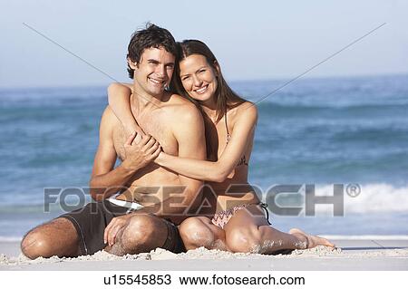 Young Couple Relaxing On Beach Wearing Swimwear View Large Photo Image Stock Image - Young Couple Relaxing On Beach Wearing Swimwear. Fotosearch