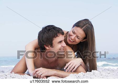 Young Couple Relaxing On Beach Wearing Swimwear View Large Photo Image Stock Image - Young Couple Relaxing On Beach Wearing Swimwear. Fotosearch