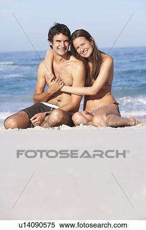 Young Couple Relaxing On Beach Wearing Swimwear View Large Photo Image Stock Photography - Young Couple Relaxing On Beach Wearing Swimwear. Fotosearch
