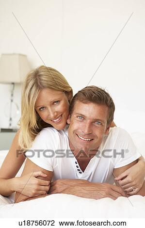 Stock Image - Young Couple Relaxing On Bed. Fotosearch