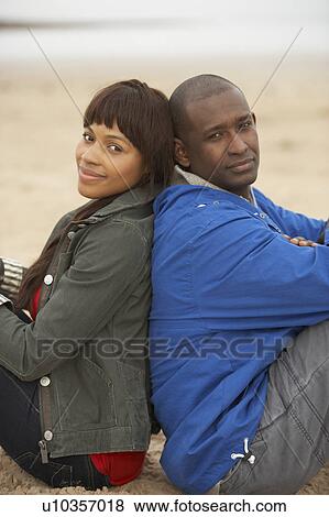 Stock Photo - Young Couple Relaxing On Winter Beach Holiday. Fotosearch