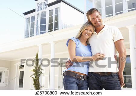 Stock Image - Young Couple Standing Outside Dream Home. Fotosearch