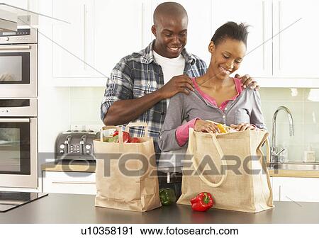 Stock Image - Young Couple Unpacking Shopping In Modern Kitchen . Fotosearch