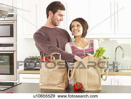 Stock Photo - Young Couple Unpacking Shopping In Modern Kitchen . Fotosearch
