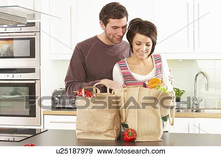 Stock Photo - Young Couple Unpacking Shopping In Modern Kitchen . Fotosearch