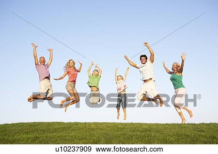 Stock Photo - Young couple with grandparents and children jump in a field. Fotosearch