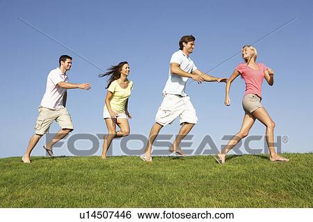 Young couples running through field View Large Photo Image Stock Photograph - Young couples running through field. Fotosearch