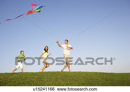 Stock Photograph - Young family, parents with child, playing in a field. Fotosearch