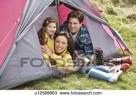 Stock Image - Young Family Relaxing Inside Tent On Camping Holiday. Fotosearch