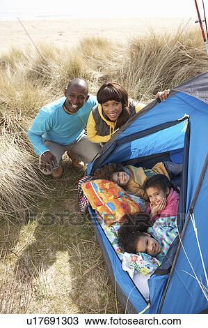 Stock Image - Young Family Relaxing Inside Tent On Camping Holiday. Fotosearch