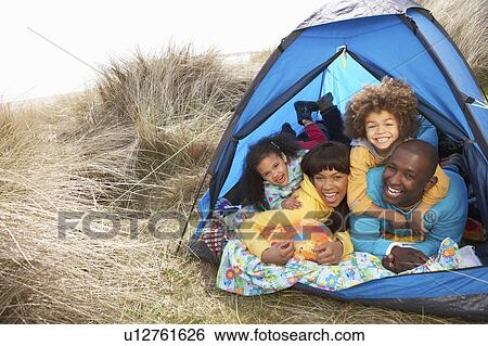 Stock Photograph - Young Family Relaxing Inside Tent On Camping Holiday. Fotosearch