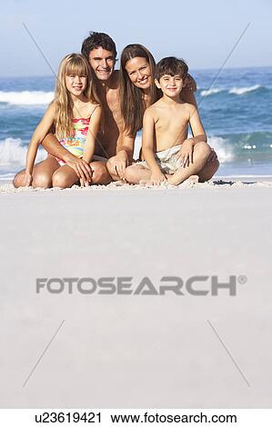 Stock Image - Young Family Relaxing On Beach Holiday. Fotosearch
