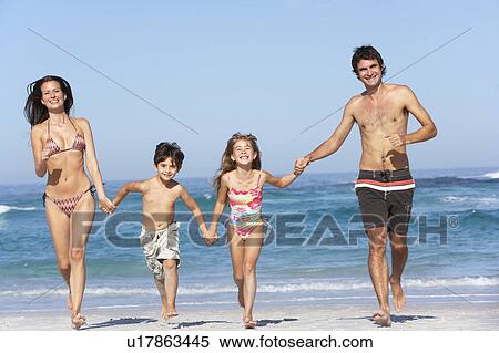 Stock Photography - Young Family Running Along Beach on Holiday. Fotosearch