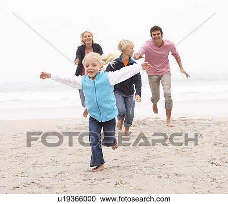 Stock Image - Young Family Running Along Winter Beach. Fotosearch
