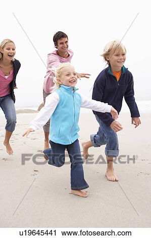 Stock Image - Young Family Running Along Winter Beach. Fotosearch