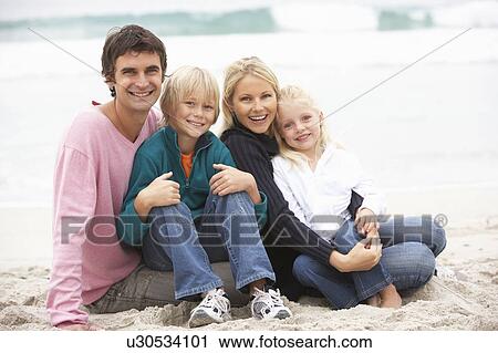 Stock Image - Young Family Sitting On Winter Beach. Fotosearch