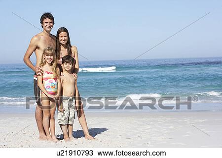 Stock Image - Young Family Standing On Sandy Beach on Holiday. Fotosearch