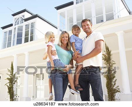 Stock Photo - Young Family Standing Outside Dream Home. Fotosearch