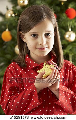 Young Girl Eating Star Shaped Christmas Cookie In Front Of Christmas Tree View Large Photo Image Stock Image - Young Girl Eating Star Shaped Christmas Cookie In Front Of Christmas Tree. Fotosearch