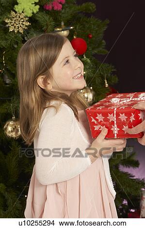 Young Girl Holding Christmas Present In Front Of Christmas Tree View Large Photo Image Picture - Young Girl Holding Christmas Present In Front Of Christmas Tree. Fotosearch